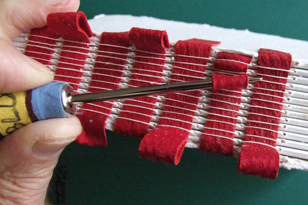 A blunt awl working on the spine of an Arkwright book